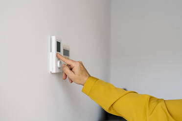 Mature woman adjusting thermostat at home - EGAF02055