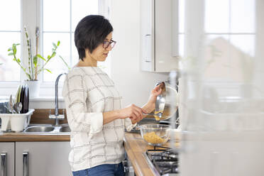 Woman crumbling biscuits to bake a cheesecake - WPEF04202