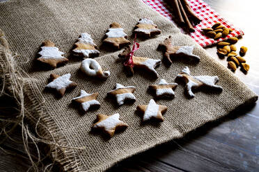 Lebkuchen und Butterkekse in Form von Weihnachtsbaum, Sternen und Rentieren auf Leinwand Tischset auf Holztisch Hintergrund, Italien, Europa - RHPLF19358