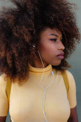 Schwarze Frau mit Afro-Haar, die mit einem Rucksack auf dem Rücken Musik hört - ADSF21253