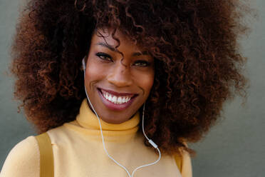 Schwarze Frau mit Afro-Haar, die mit einem Rucksack auf dem Rücken Musik hört - ADSF21254