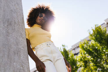 Schwarze Frau mit Afro-Haar posiert vor einer grauen Wand und schaut in die Kamera - ADSF21263