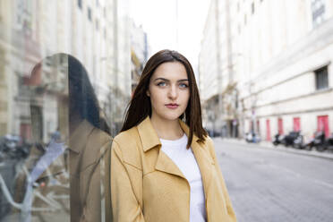 Woman with blue eyes by glass wall in city - JCCMF01395