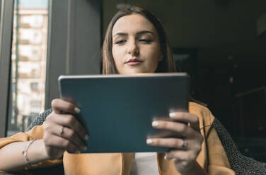 Beautiful woman using digital tablet while sitting at coffee shop - JCCMF01417