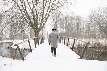 Mid adult man walking on bridge in winter - AXHF00200