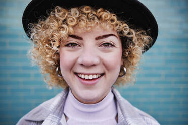 Lächelnde Frau mit lockigem Haar und Hut - ASGF00055