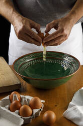 Mid section of man cracking chicken egg into bowl - IFRF00449