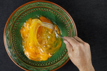 Hand of man mixing egg yolks in green bowl - IFRF00450