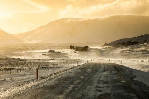 Empty road leading to residential houses located in highland valley in winter in Iceland - ADSF21357