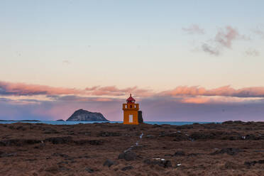 Wunderschöne Landschaft des Leuchtfeuers an der Küste vor dem Meer auf dem Hintergrund des Sonnenuntergangs Himmel in Island - ADSF21360