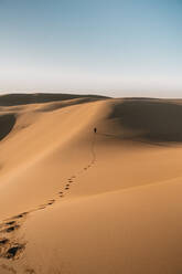 Remote view of person walking on dunes in desert in Australia and leaving footprints on sand - ADSF21428