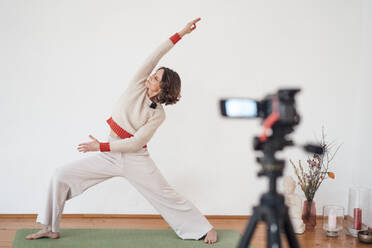 Woman filming herself while practicing Yoga at health studio - MOEF03666
