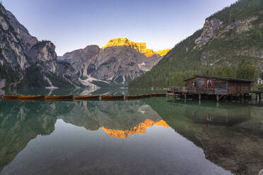 Reflection of Croda del Becco mountain in Pragser Wildsee lake by log cabin at Dolomites, Alto Adige, Italy - LOMF01253