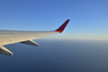 Tragfläche eines Verkehrsflugzeugs gegen einen klaren blauen Himmel - RUEF03238