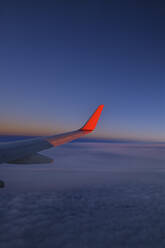 Wing of commercial airplane flying against sky at dusk - RUEF03241