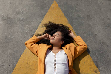 Young woman with eyes closed lying down on footpath - TCEF01656