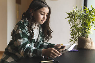 Mädchen beim E-Learning über ein digitales Tablet am Wohnzimmertisch - JAQF00358