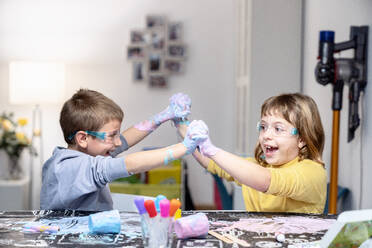 Cheerful siblings playing with slime at home - AMPF00115