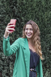 Lächelnde Frau nimmt Selfie durch Smartphone im Park - JRVF00358