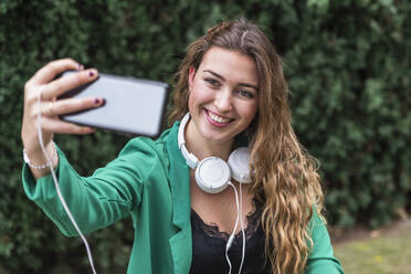 Glückliche Frau nimmt Selfie durch Handy im Park - JRVF00366