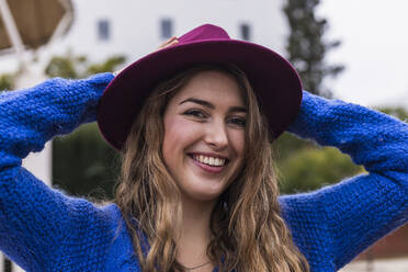 Happy woman wearing hat at park - JRVF00369