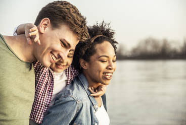 Cheerful parents with son by lake during sunset - UUF23000