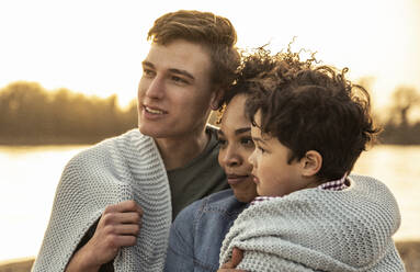 Familie in Decke gehüllt bei Sonnenuntergang - UUF23011