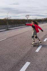 Woman skating with skateboard on road - RSGF00585