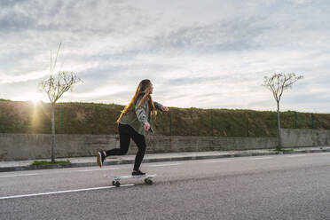 Young female skater balancing on skateboard - RSGF00610