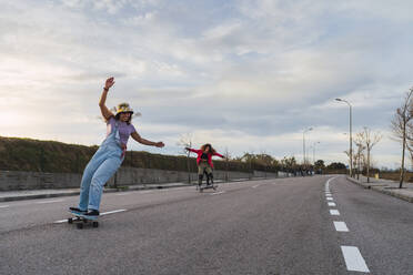 Female friends having fun while riding skates on road - RSGF00611