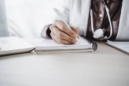Female medical professional writing in diary - EBBF02654
