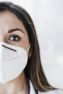 Close up of female doctor by the window wearing face mask - EBBF02685