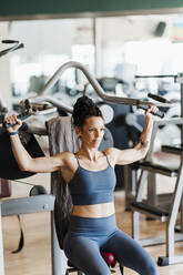 Muskulöse Sportlerin beim Training an Geräten im Fitnessstudio - EBBF02716