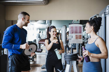 Male and female athlete friends talking while standing in gym - EBBF02727