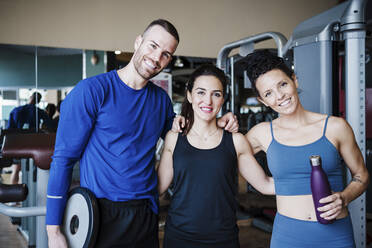 Lächelnde Sportler mit Arm um stehen im Fitnessstudio - EBBF02728