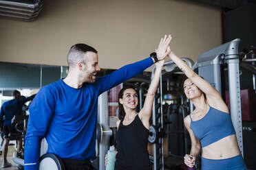 Cheerful male and female athlete giving high-five in gym - EBBF02729