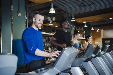 Männliche und weibliche Sportler laufen auf dem Laufband im Fitnessstudio - EBBF02736