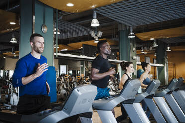 Männliche und weibliche Sportler beim Training auf dem Laufband im Fitnessstudio - EBBF02741