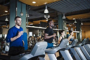 Male and female sports people exercising on treadmill in health club - EBBF02741