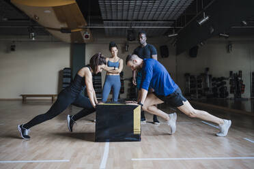 Männliche und weibliche Sportler beim Boxenschieben in der Turnhalle - EBBF02750