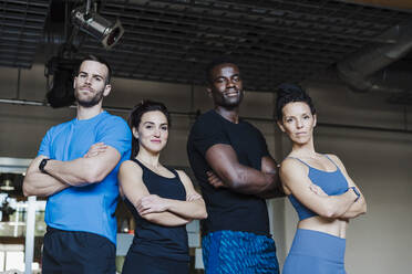 Multi-ethnic group of sports people with arms crossed standing in gym - EBBF02774