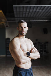 Handsome young male athlete with arms crossed in health club - EBBF02792