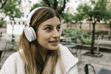 Frau mit Kopfhörern, die lächelnd wegschaut, im Freien - XLGF01312