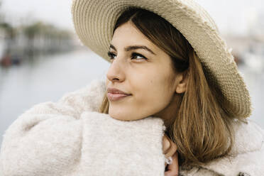 Woman in hat looking away while day dreaming outdoors - XLGF01320