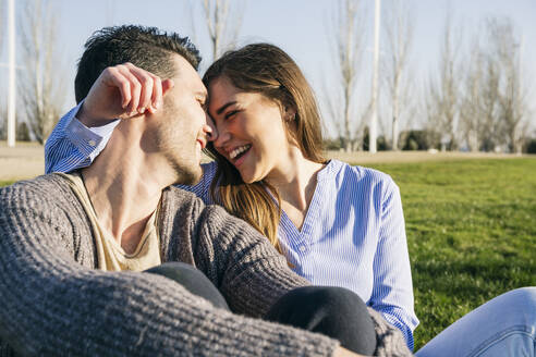 Girlfriend sitting face to face with boyfriend at park - ABZF03479