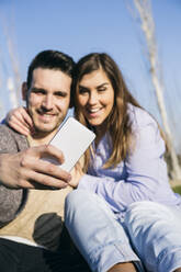 Freund nimmt Selfie durch Handy mit Freundin im Park - ABZF03482