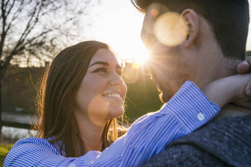 Smiling woman looking at man during sunset - ABZF03508