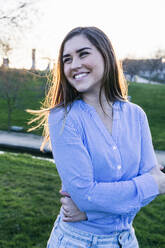 Beautiful woman smiling in park during sunset - ABZF03512