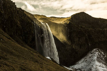 Erstaunlicher Blick auf einen mächtigen Wasserfall in felsigem Hochlandgelände an einem sonnigen Tag in Island - ADSF21441