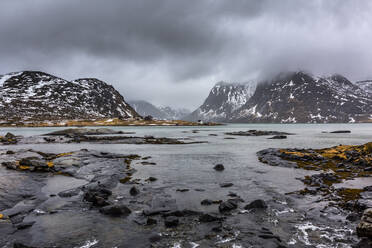 Wunderschöne Landschaft von Meer und Bergen unter grauem, bewölktem Himmel im Winter in Norwegen - ADSF21461